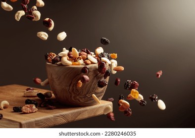 Flying dried fruits and nuts. The mix of nuts and dried berries are in a wooden bowl.  - Powered by Shutterstock