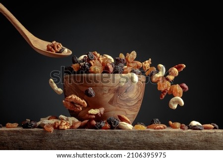 Flying dried fruits and nuts. The mix of dried nuts and raisins in a wooden bowl. Copy space.