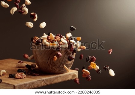 Flying dried fruits and nuts. The mix of nuts and dried berries are in a wooden bowl. 