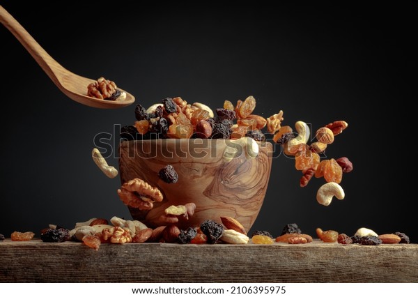 Flying dried fruits and nuts.\
The mix of dried nuts and raisins in a wooden bowl. Copy\
space.