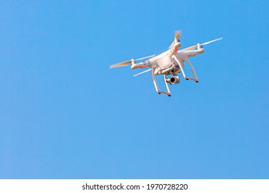 Flying drone quadcopter with a camera against blue sky.