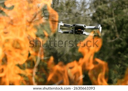 Flying drone Quadcopter with camera pointed at viewer outdoor in a fire in the foreground spurts of flame on forest background