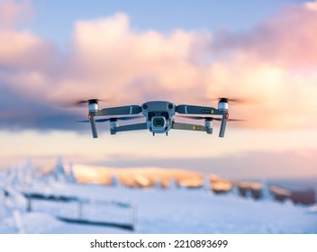 Flying drone with snowy mountains landscape and colorful clouds - Powered by Shutterstock