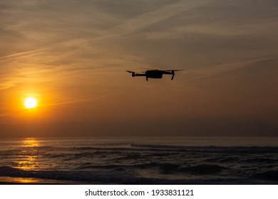 Flying drone in the sunset by the sea - Shutterstock ID 1933831121