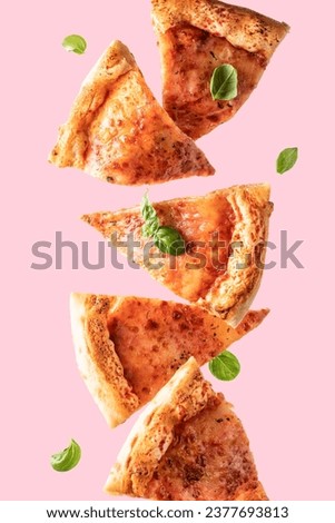 Flying food. Pizza margherita slices with cheese and basil leaves in levitation on pink background. Vertical orientation