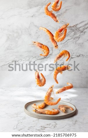 Flying food. Seafood shrimps prawns fly over gray plate, Marbled background.