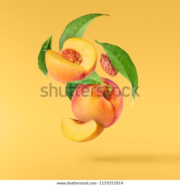 Flying\
fresh ripe peach with green leaves isolated on yellow background.\
Concept of food levitation, high resolution\
image