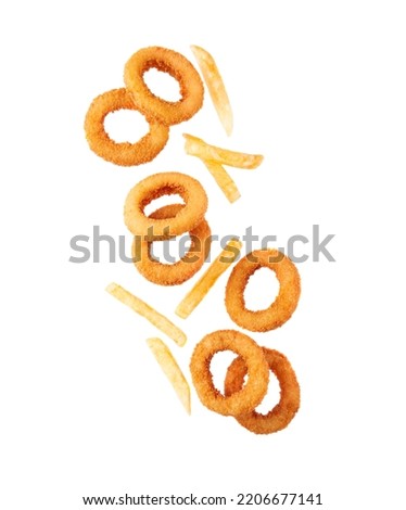 Flying fried potatoes and onion rings close up on white backgrounds.Fast food