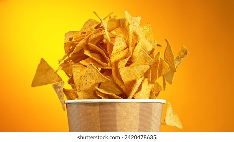 Flying Fried Tortilla Chips Exploding from Paper Bucket. Concept of Flying Junk Food.