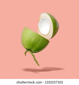 Flying green coconut on a pastel pink background, creative summer food concept, floating young coconut in the air with clipping path
