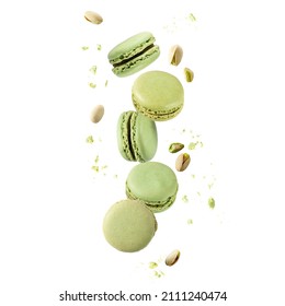 Flying green sweet pistachio macarons macaroons with crumbs and nuts isolated on white background