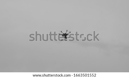 Flying helicopter dron on a background of white clouds
