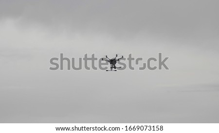 Flying helicopter dron on a background of white clouds