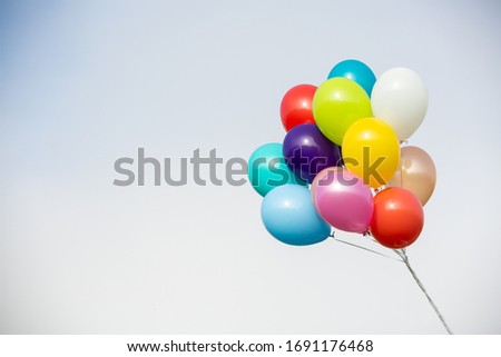 Flying helium baloons against bright sky