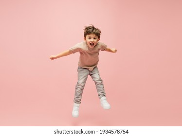 Flying high. Happy, smiley little caucasian boy isolated on pink studio background with copyspace for ad. Looks happy, cheerful. Childhood, education, human emotions, facial expression concept.