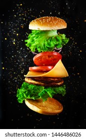 Flying ingredients for a homemade burger on a black background. Not diet food, unhealthy food.