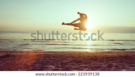 flying kick on the beach at dawn. martial arts and fitness
