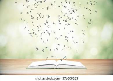 Flying letters from the opened book on wooden table - Powered by Shutterstock