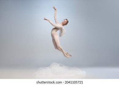 Flying like a feather. Young and graceful ballet dancer, ballerina dancing in image of angel with wings isolated on gray studio background. Solo art performance. Beauty, flexibility, inspiration