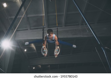 Flying. Little male gymnast training in gym, composed and active. Caucasian fit boy, athlete in sportswear practicing in exercises for strength, balance. Movement, action, motion, dynamic concept.