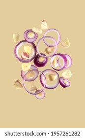 Flying Onion Rings And Sliced Garlic Cloves Isolated On A Beige Background