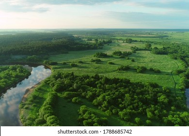 Flying over bend of the river and forest on island inside it in natural beautiful wild landscape. Aerial view of picturesque background, aerial panoramic view of natural park at sunny summer day.