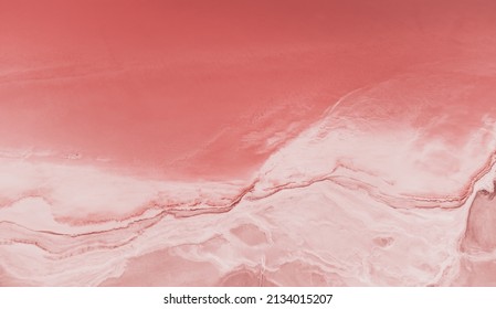 Flying over a pink salt lake. Salt production facilities saline evaporation pond fields in the salty lake. Dunaliella salina impart a red, pink water in mineral lake with dry cristallized salty coast