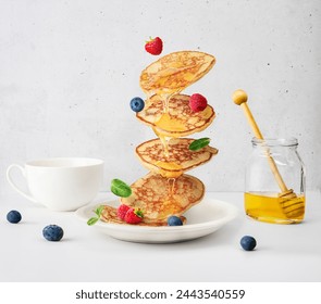 Flying pancakes with honey and berries over white table - Powered by Shutterstock