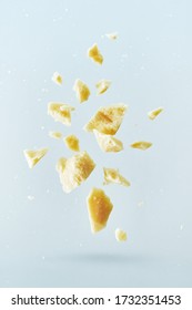 Flying parmesan cheese explodes and splits in different directions with crumbs isolated on a white background. 