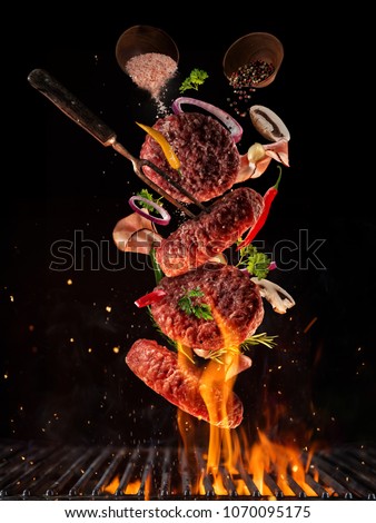 Flying pieces of beef meat pieces on hamburger from grill grid, isolated on black background. Concept of flying food, very high resolution image