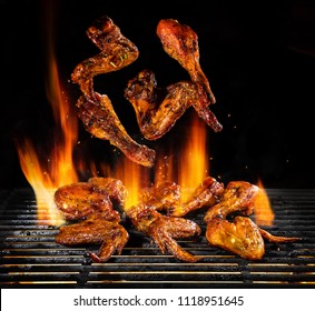 Flying pieces of chicken meat on grill with Fire flames. Isolated on black background. Barbecue and grilling. Very high resolution image