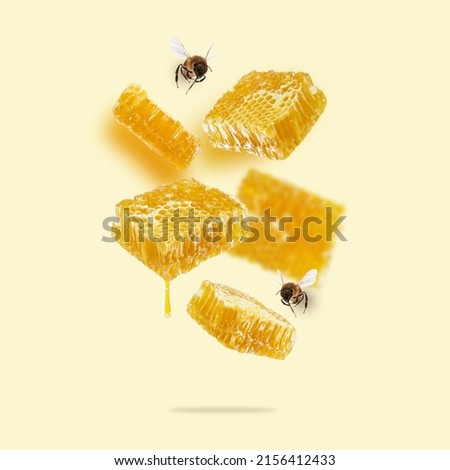 Flying pieces of honeycomb, drop of honey and bees on a yellow background. A conceptual composition of floating honeycombs. Healthy food, square image. Creative layout design.