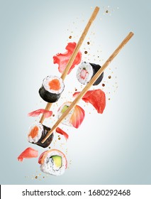 Flying pieces of sushi with chopsticks on light background. Concept of flying sushi with ingredients. With clipping path.