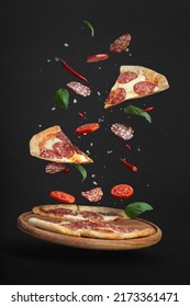 Flying Pizza With Ingredients On A Black Background