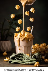 Flying popcorn with milkshake with caramel and pop corn topping in glass, levitation and dark photography. Summer healthy dessert concept