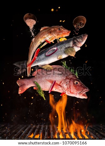 Flying raw whole fish from grill grid, isolated on black background. Concept of flying food, very high resolution image