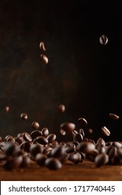 Flying roasted brown coffee beans on wooden background. Selective focus