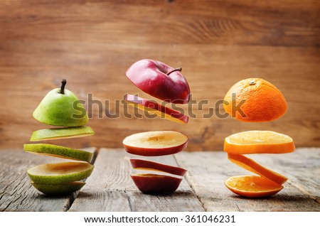 flying slices of fruit: apple, pear, orange on a dark wood background. toning. selective Focus