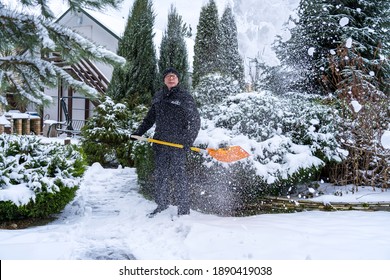 Flying Snow Thrown By An Elderly Man With An Orange Shovel. Winter Old Age Lifestyle Concept