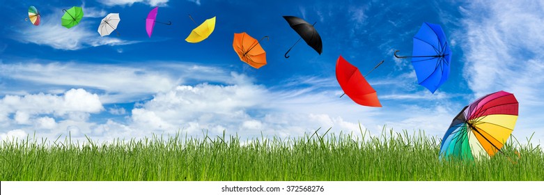 flying umbrellas in front of blue sky and green natural grass