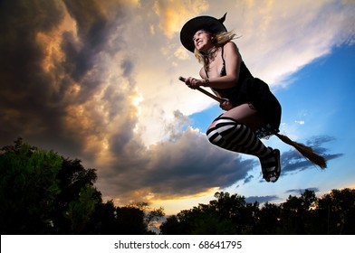 Flying witch on broomstick in the evening