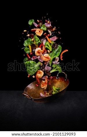 Flying wok ingredients - shrimp, vegetables, pak choi leaves, onions and peanuts. Asian food delivery. Chinese recipes. Wok preparation ingredients. Vertical image.