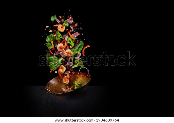 Flying wok ingredients - shrimp,\
vegetables, pak choi leaves, onions and peanuts. Asian food\
delivery. Chinese recipes. Wok preparation ingredients. Copy\
space