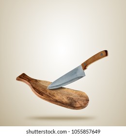 Flying wooden cutting board with knife, isolated on gradient brown background. Food preparation concept. Very high resolution image