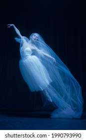 Flying. Young Graceful Beautiful Woman, Balerina In White Wedding Dress In Art Performance Isolated On Dark Background In Neon Light. Concept Of Love, Relationship, Beauty, Art And Theater.