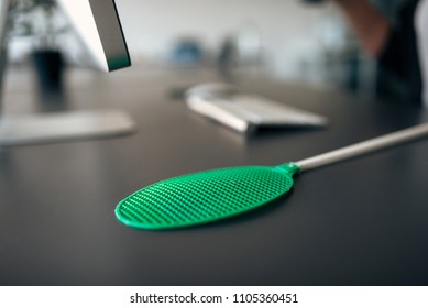 Flyswatter On Office Desk.