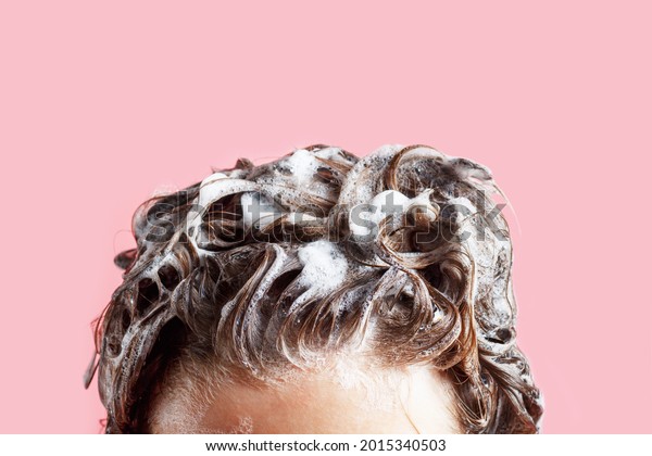Fmale\
hair shampoo and foam on pink background\
close-up.