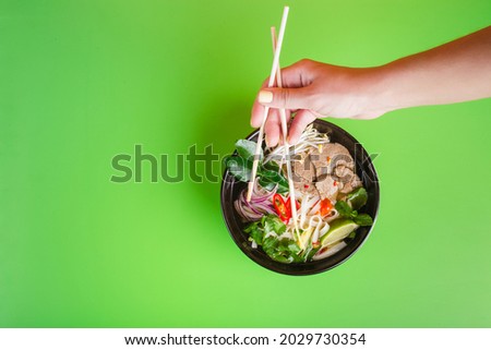 Fo Bo - Vietnamese Beef Soup on green woman hand with sticks