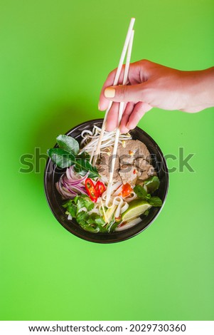 Fo Bo - Vietnamese Beef Soup on green woman hand with sticks