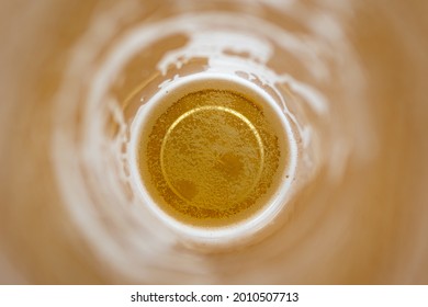 Foam and bubbles in a half-empty beer glass top view. abstract beer background
